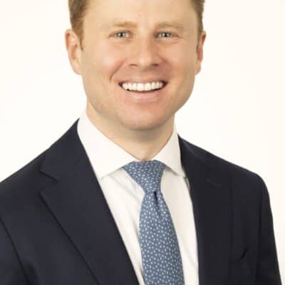 a man wearing a suit and tie smiling at the camera